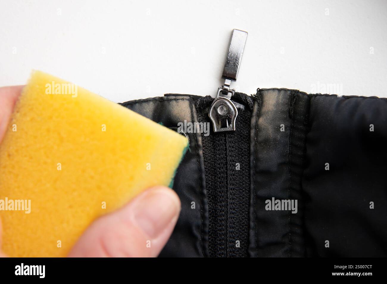 Rimozione delle macchie di base per il trucco beige dal rivestimento nero con una spugna per pulizia e un liquido per lavastoviglie a casa. Foto Stock