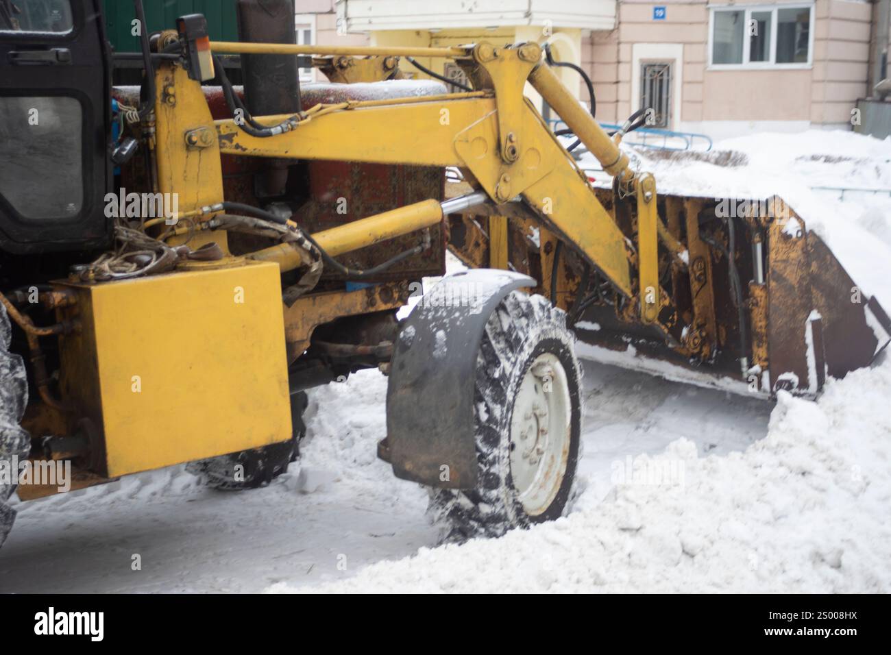 Macchinari pesanti per strada in inverno. Rimozione della neve con una benna. Foto Stock
