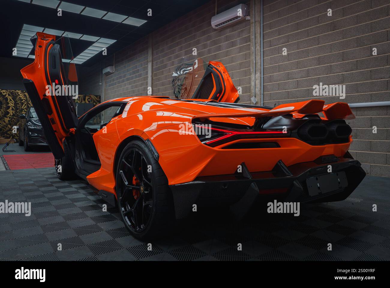 Lamborghini Revuelto arancione con porte a forbice in ambiente interno Foto Stock