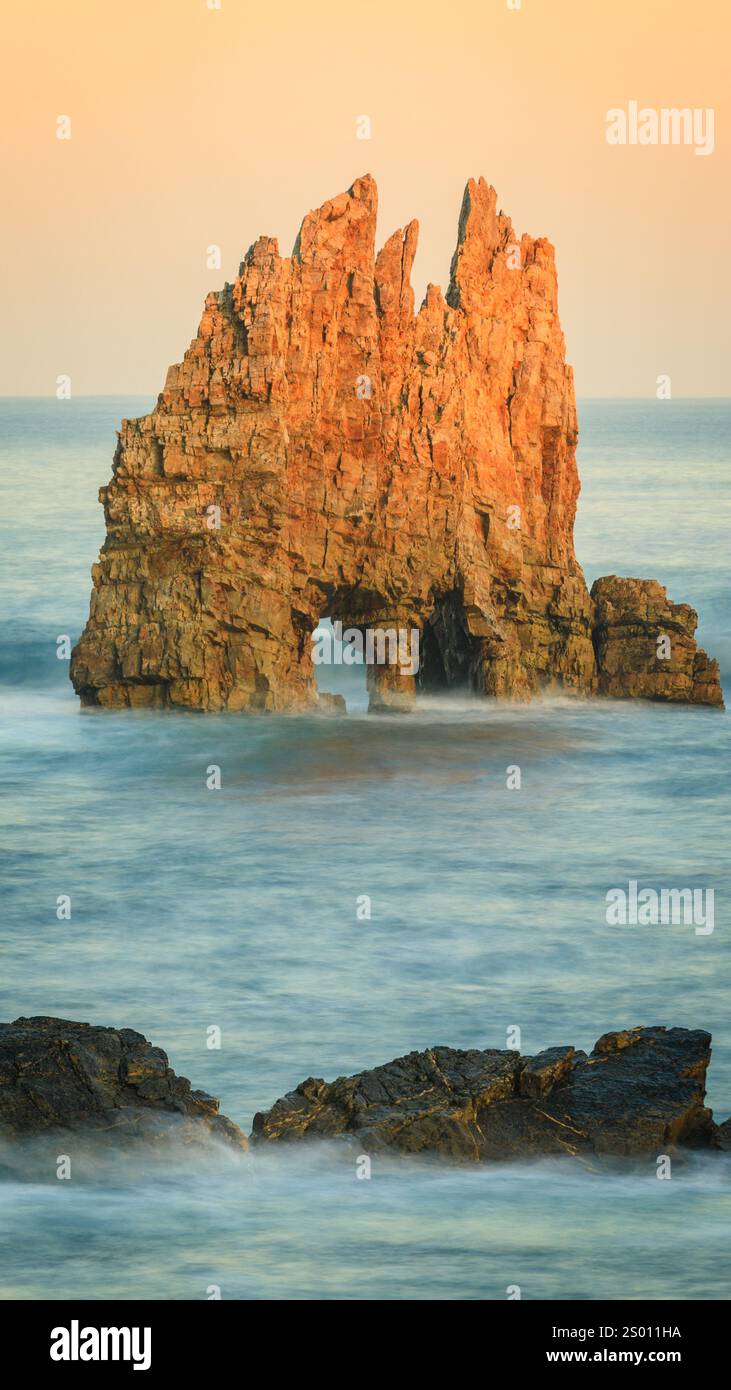 Formazione rocciosa a Portizuelo Beach nel nord della Spagna, con scogliere frastagliate che si innalzano dall'oceano, creando un suggestivo arco naturale, Foto Stock