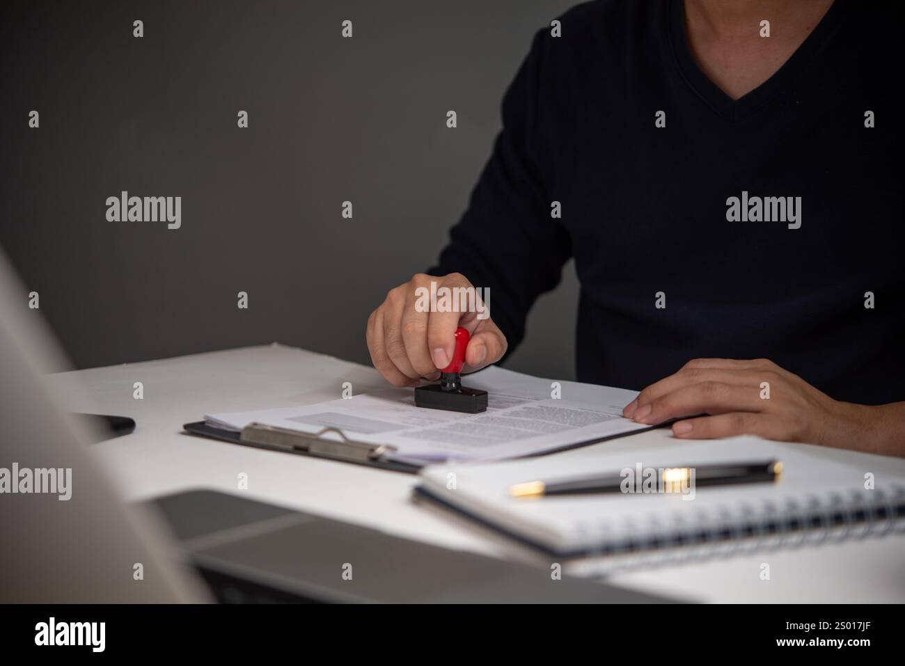 Imprenditore che timbra un documento ufficiale per l'approvazione, simboleggiando l'autorità, la convalida e la conformità nel lavoro amministrativo. Foto Stock
