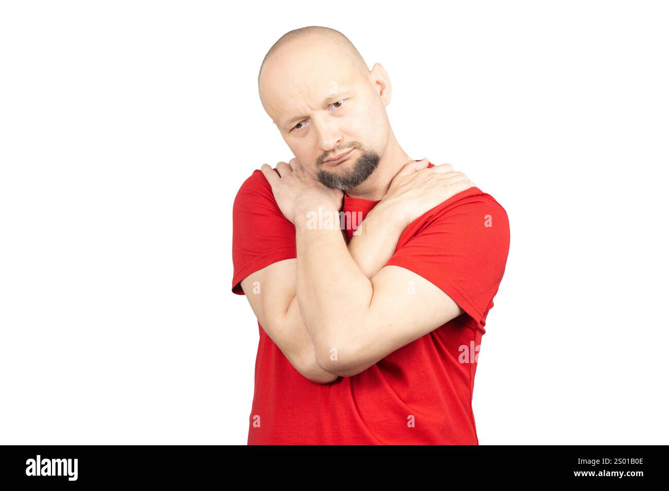 Un uomo che indossa una T-shirt rossa si vede tenere entrambe le spalle con le mani, esprimendo dolori muscolari e articolari. Foto Stock