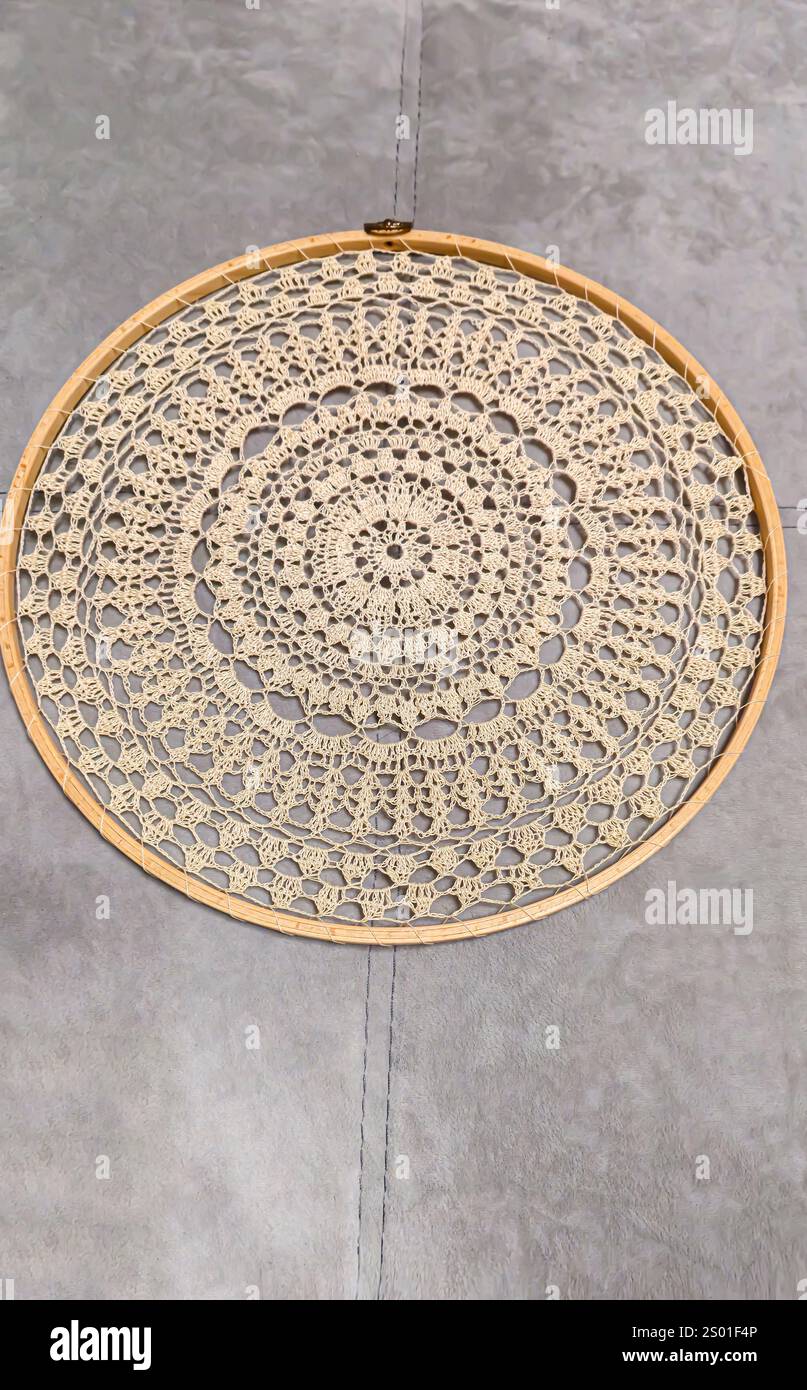 Tovagliolo a uncinetto su telaio in legno. Mandala con diversi motivi decorativi, sfondo in legno fatto a mano Foto Stock