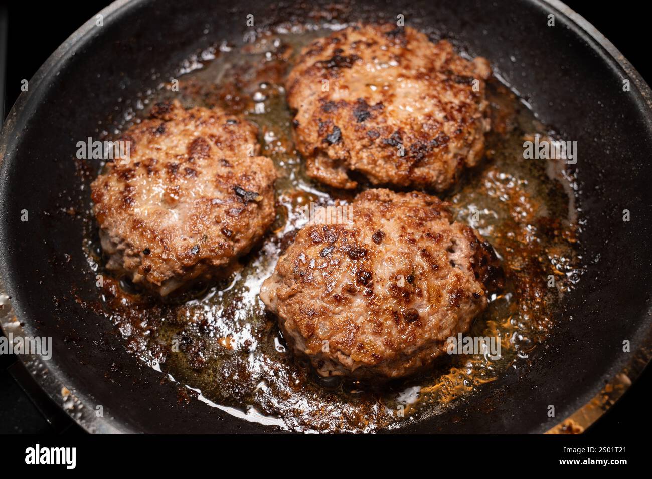 Tre polpette di manzo sminuzzate svedesi spolverano nel burro dorato, friggendo alla perfezione in una padella calda. Foto Stock
