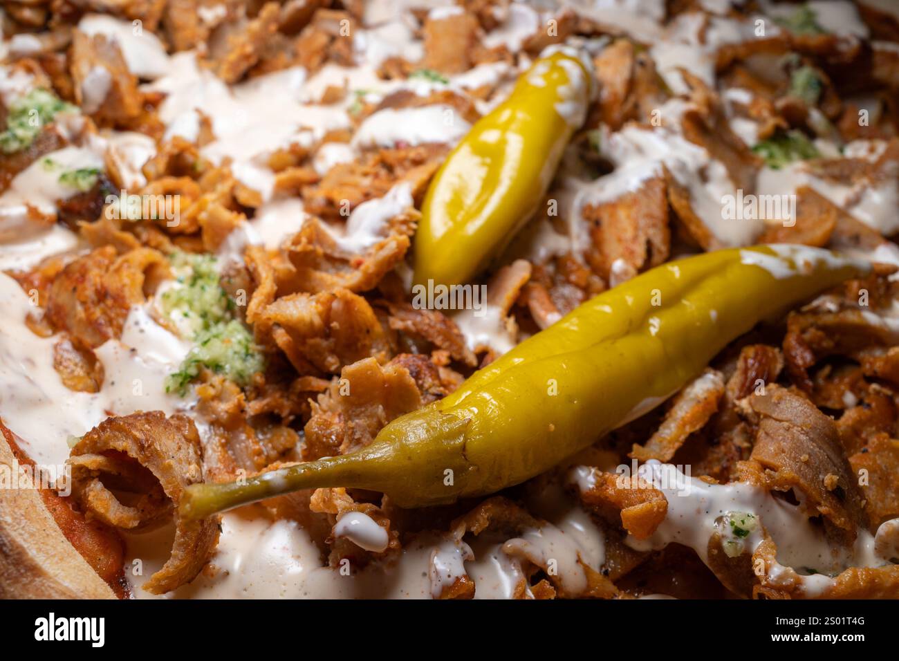 Un primo piano della famosa pizza kebab svedese mette in mostra i suoi sapori audaci, con peperoni fefferoni verdi e salsa cremosa all'aglio che esalta il suo ricco e ricco Foto Stock