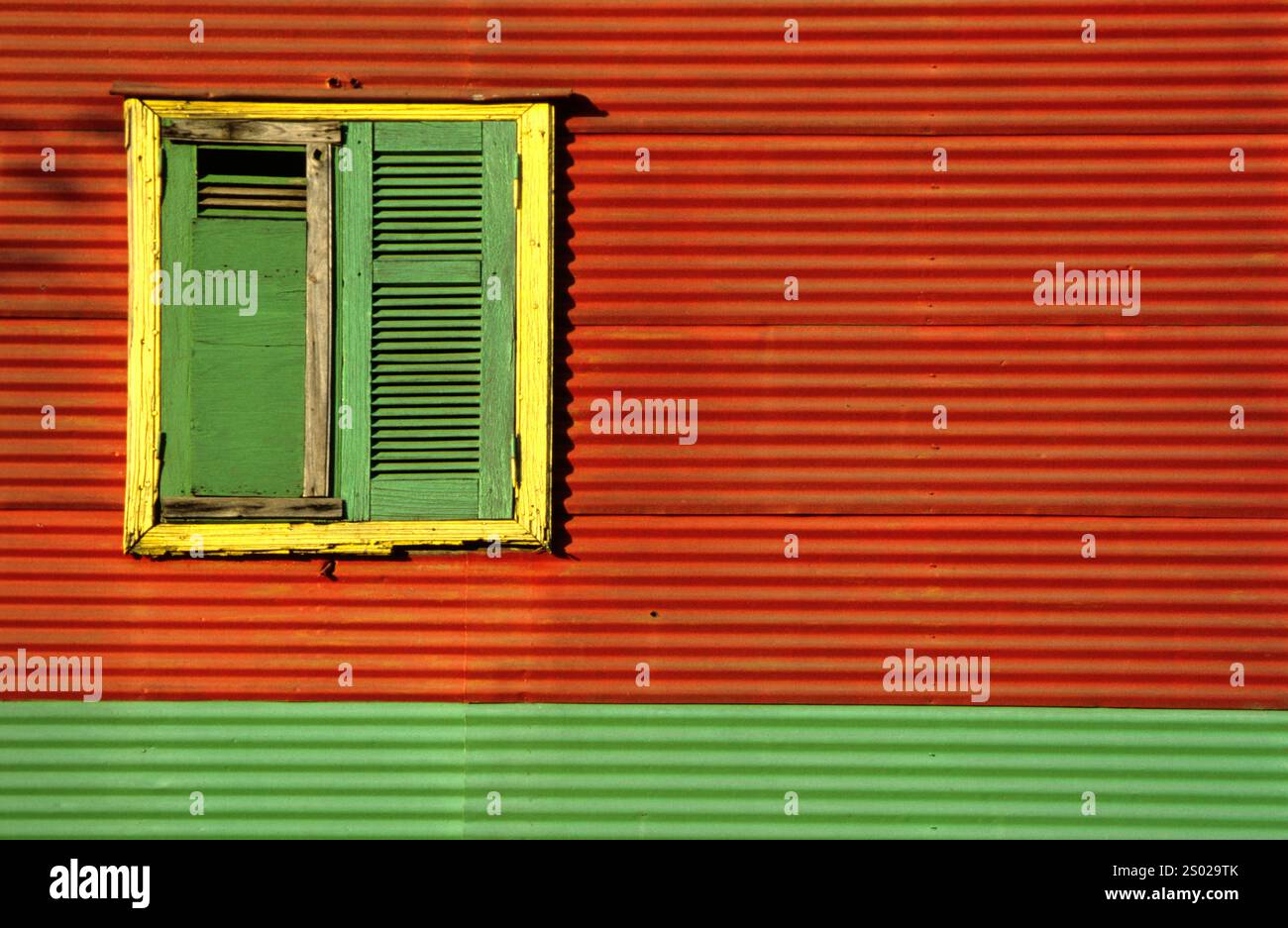 Vibrante facciata in metallo ondulato con una finestra verde e gialla a la Boca, Buenos Aires, Argentina, che riflette la sua architettura colorata. Foto Stock