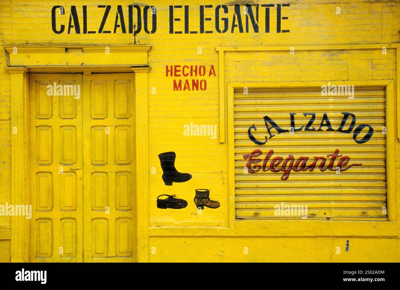 Negozio Calzado elegante con facciata gialla brillante in El Salvador, che mostra pubblicità di scarpe fatte a mano e artigianato tradizionale. Foto Stock