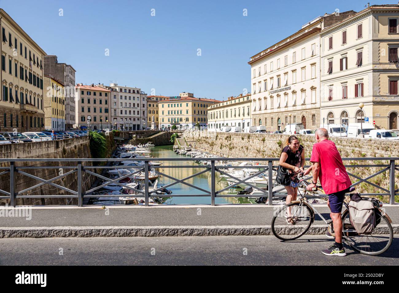Livorno Italia, sistema di canali di fossato del Fosso reale, barche attraccate lungo il canale, Ponte dei francesi, bicicletta ciclista, uomo donna vicini res Foto Stock