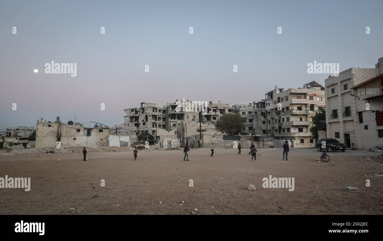 Hama, Siria. 14 dicembre 2024. I bambini giocano a calcio in un quartiere di Ghouta orientale che è ancora in gran parte distrutto a seguito di un assedio di cinque anni da parte dei militari del regime di Assad tra il 2013 e il 2018. Un'offensiva ribelle d'urto portò alla caduta del regime di Bashar al-Assad l'8 dicembre 2024. Credito: SOPA Images Limited/Alamy Live News Foto Stock