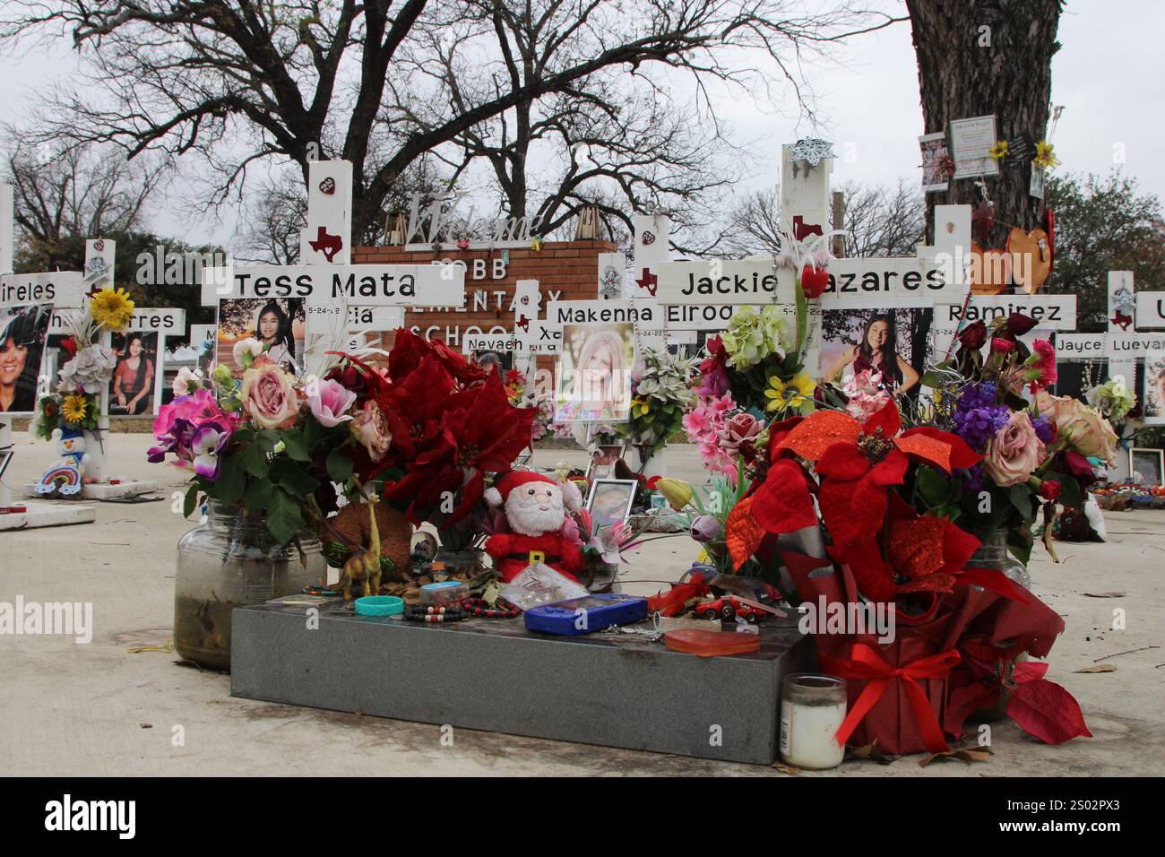 Uvalde, Stati Uniti. 23 dicembre 2024. Una bambola di Natale ripiena di Babbo Natale e due Poinsettias fanno parte del memoriale delle riprese della Robb Elementary School a Uvalde, Texas, USA, il 23 dicembre 2024. Nel maggio dell'anno 2022 un adolescente ha ucciso 19 studenti e due insegnanti alla Robb Elementary School. (Foto di Carlos Kosienski/Sipa) credito: SIPA USA/Alamy Live News Foto Stock