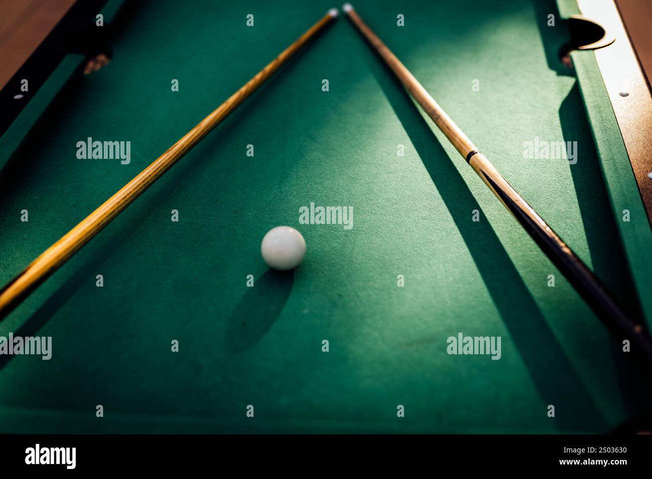 Un tavolo da biliardo con palle da biliardo sparse, un bastoncino e accessori catturati in una scena dinamica e pronta per il gioco. L'attenzione dettagliata sull'apparecchiatura Foto Stock