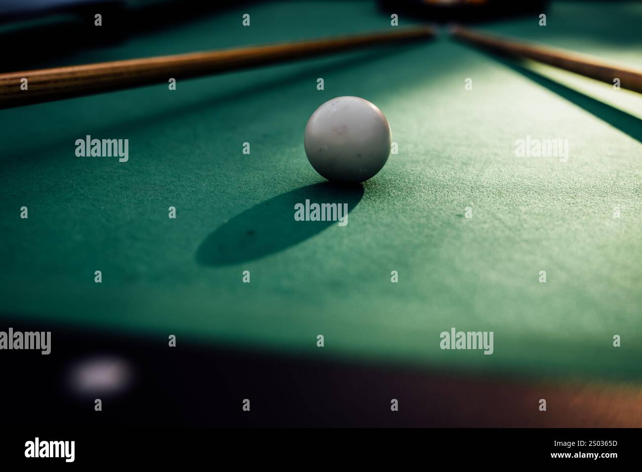 Un tavolo da biliardo con palle da biliardo sparse, un bastoncino e accessori catturati in una scena dinamica e pronta per il gioco. L'attenzione dettagliata sull'apparecchiatura Foto Stock