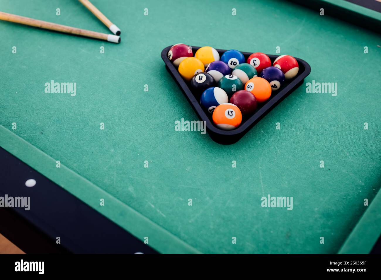 Un tavolo da biliardo con palle da biliardo sparse, un bastoncino e accessori catturati in una scena dinamica e pronta per il gioco. L'attenzione dettagliata sull'apparecchiatura Foto Stock