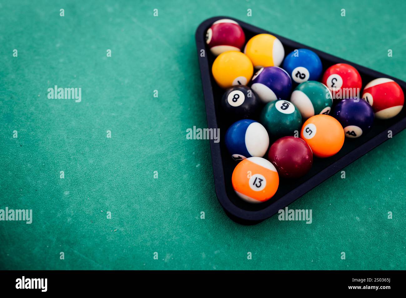 Un tavolo da biliardo con palle da biliardo sparse, un bastoncino e accessori catturati in una scena dinamica e pronta per il gioco. L'attenzione dettagliata sull'apparecchiatura Foto Stock