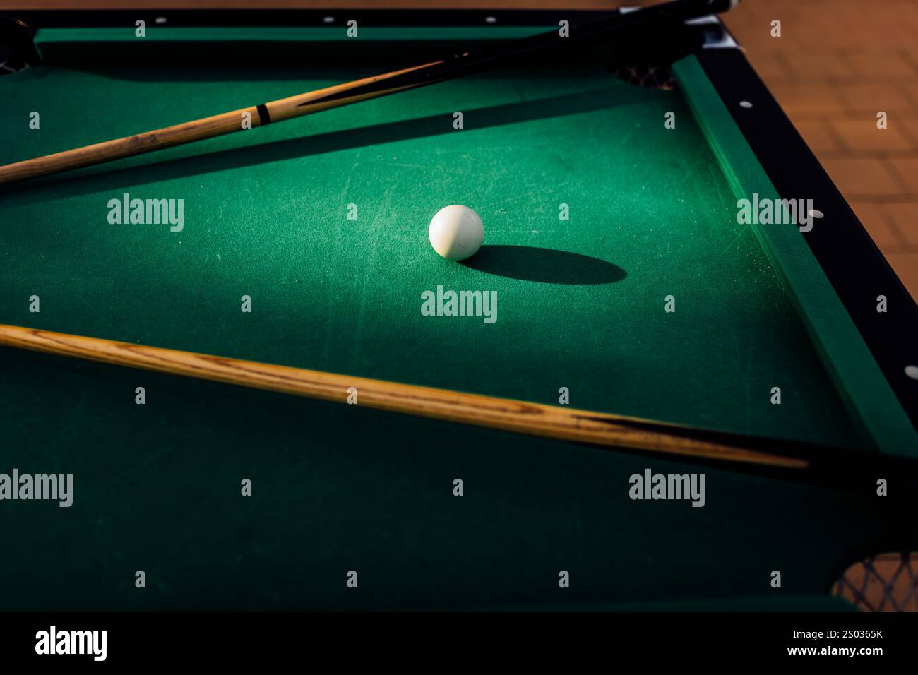 Un tavolo da biliardo con palle da biliardo sparse, un bastoncino e accessori catturati in una scena dinamica e pronta per il gioco. L'attenzione dettagliata sull'apparecchiatura Foto Stock