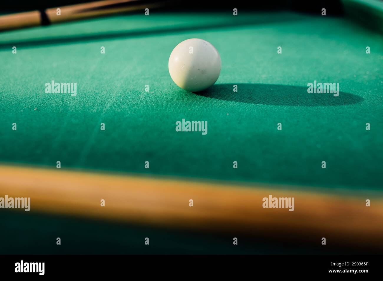 Un tavolo da biliardo con palle da biliardo sparse, un bastoncino e accessori catturati in una scena dinamica e pronta per il gioco. L'attenzione dettagliata sull'apparecchiatura Foto Stock