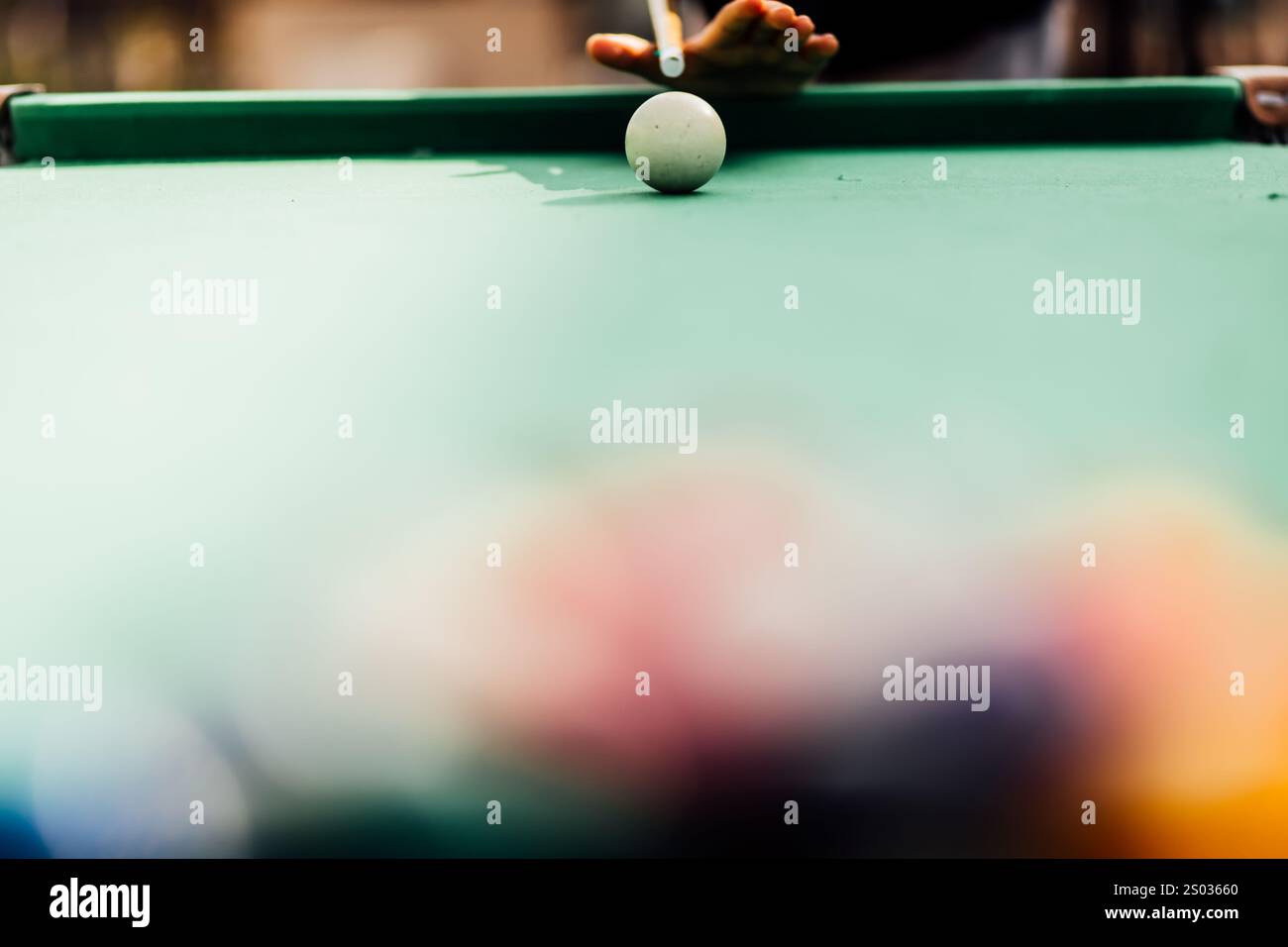 Un tavolo da biliardo con palle da biliardo sparse, un bastoncino e accessori catturati in una scena dinamica e pronta per il gioco. L'attenzione dettagliata sull'apparecchiatura Foto Stock