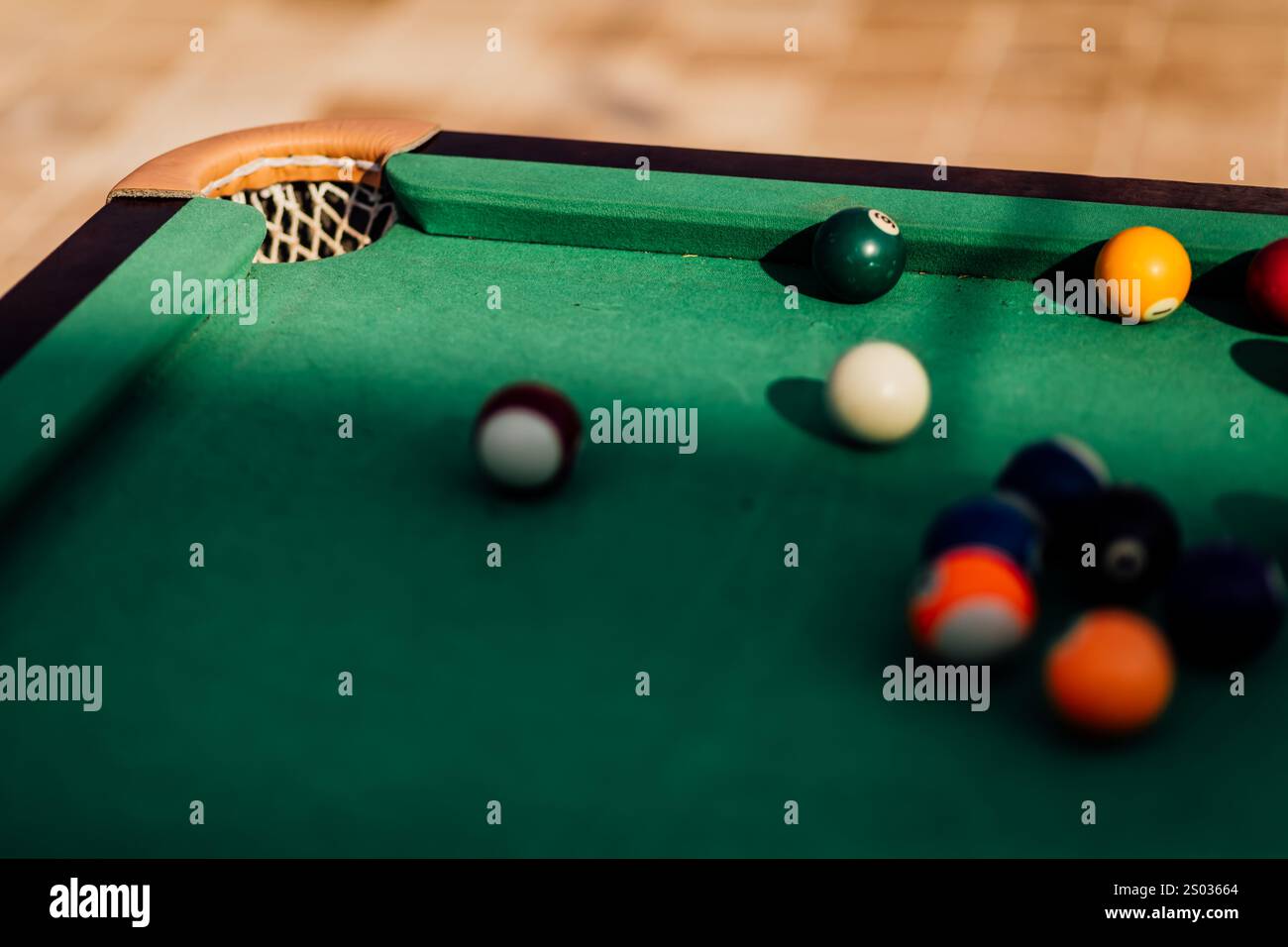 Un tavolo da biliardo con palle da biliardo sparse, un bastoncino e accessori catturati in una scena dinamica e pronta per il gioco. L'attenzione dettagliata sull'apparecchiatura Foto Stock