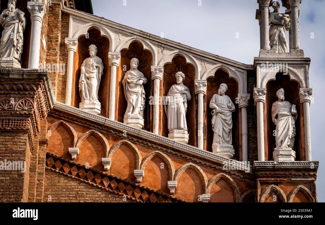 Vista ravvicinata della facciata di un edificio storico con sculture ornate di figure in abbigliamento classico, adagiate su un cielo nuvoloso. Foto Stock