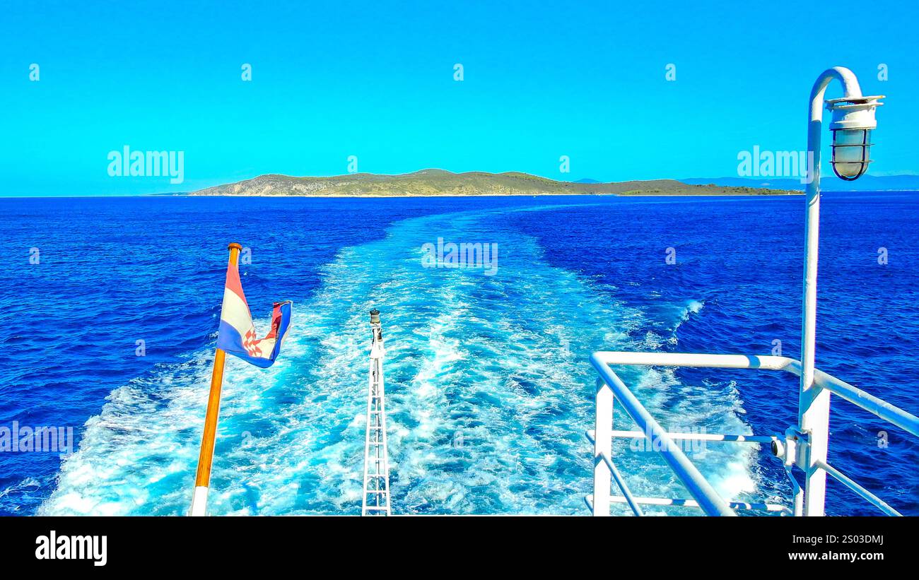 Bandiera croata che sventola sull'albero della nave, onde agitate dalle eliche di un grande motoscafo, vista della poppa della nave Foto Stock