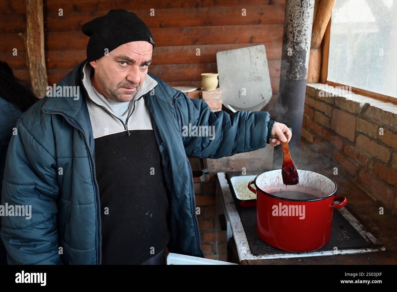 Ohrady, Dunajská Streda, Slovacchia - novembre 30 2024: Massacro di maiale della comunità tradizionale del villaggio (zabíjačka), uomo che cucina il sangue di maiale Foto Stock