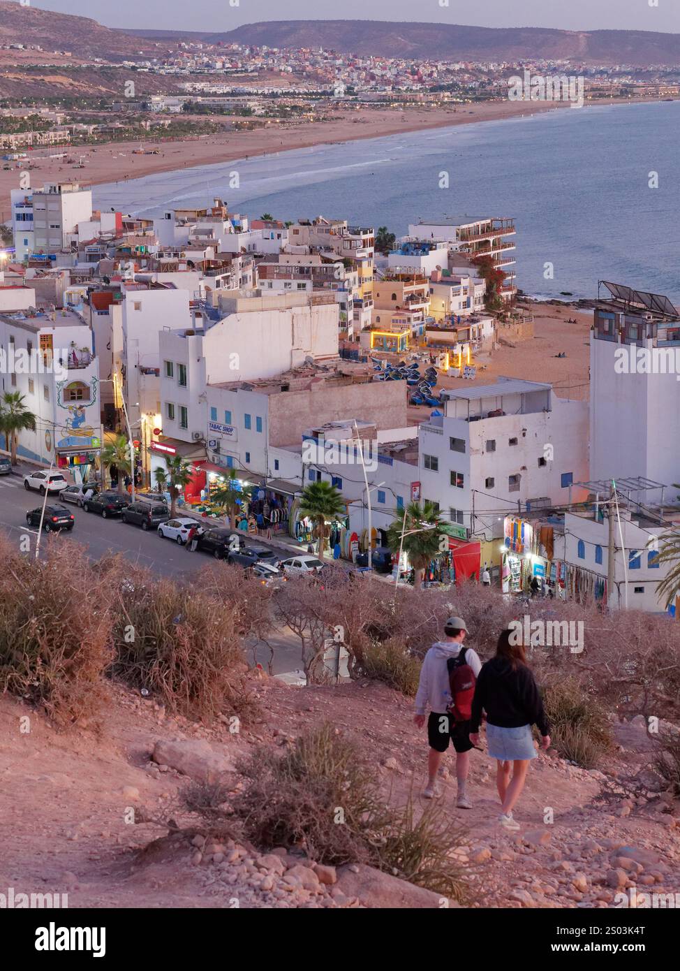 Villaggio turistico di Taghazout e spiaggia sabbiosa lungo la costa atlantica vista da una piccola collina in serata in Marocco. 23 dicembre 2024 Foto Stock