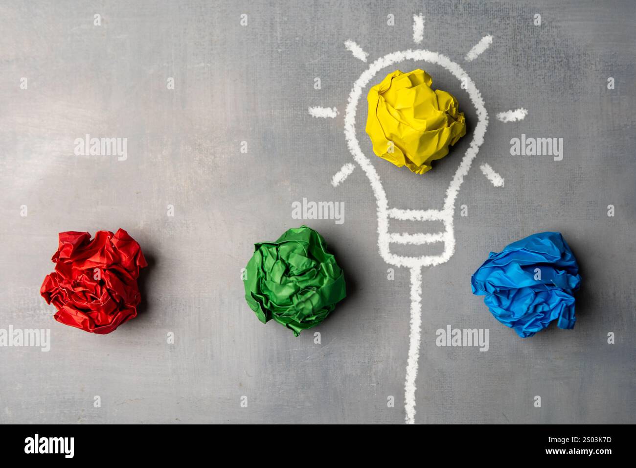 Un'immagine piatta di una lampadina disegnata su una lavagna con pezzi di carta increspati. Processo creativo e generazione di idee. Foto Stock