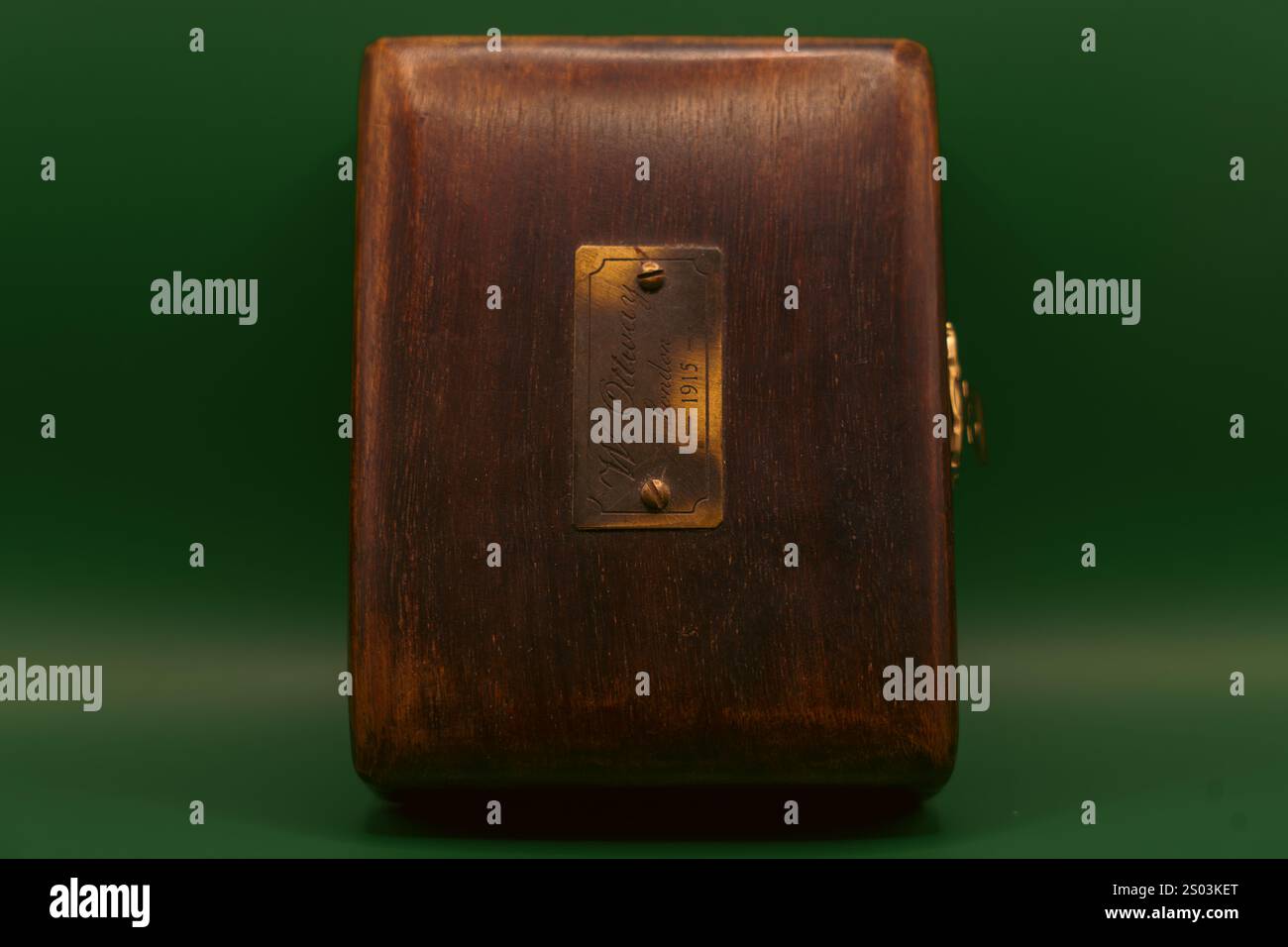 Antica scatola in legno con lastra in ottone incisa "W. Ottway, London, 1915", fotografata su sfondo verde. Foto Stock