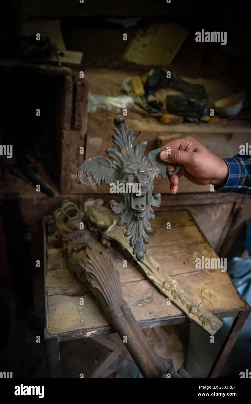 Un dettaglio di artigianato in bronzo, sapientemente fatto a mano in un laboratorio di strada di Alessandria, Egitto. La mano dell'artigiano mette in risalto l'intricata maestria artigianale. Foto Stock
