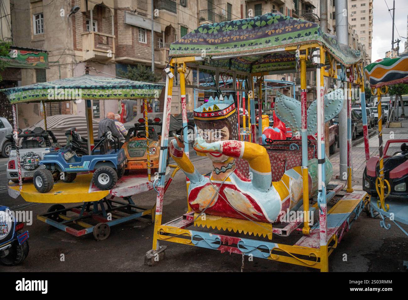 Una giostra colorata per bambini d'epoca per le strade di Alessandria, Egitto, con vivaci disegni della fiera e figure stravaganti. Foto Stock