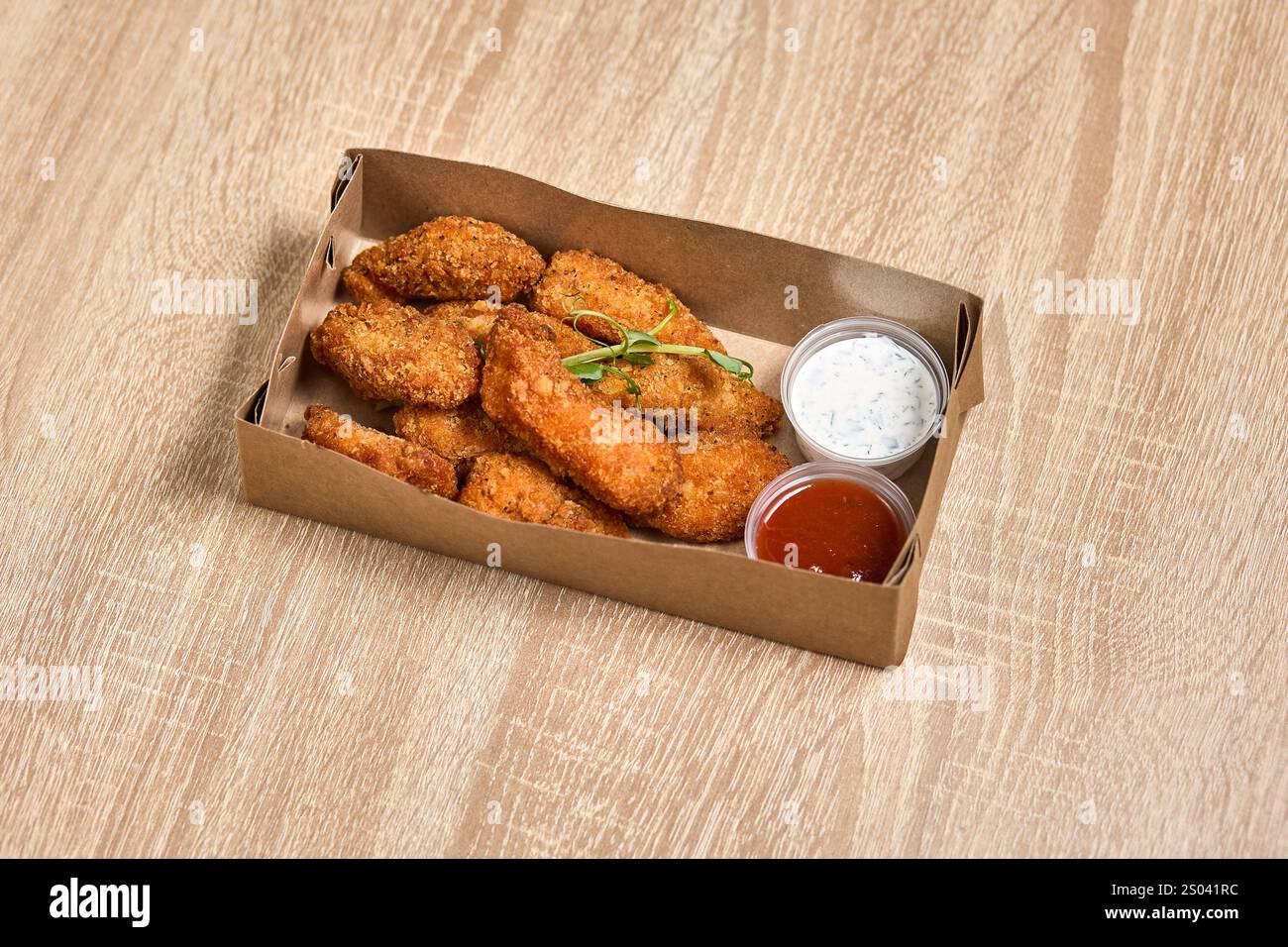 Pepite di pollo impanate con ketchup e salsa all'aglio in una scatola da asporto. Foto Stock