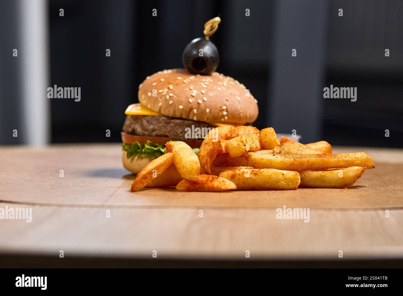 Un gustoso cheeseburger con patatine fritte croccanti, condimenti e un'oliva. Foto Stock