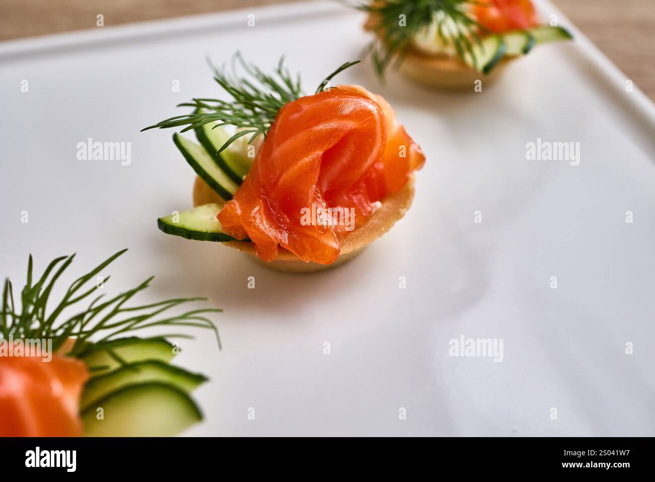 Mini tortine ripiene di formaggio spalmabile e ricoperte di salmone affumicato, cetriolo e aneto. Foto Stock