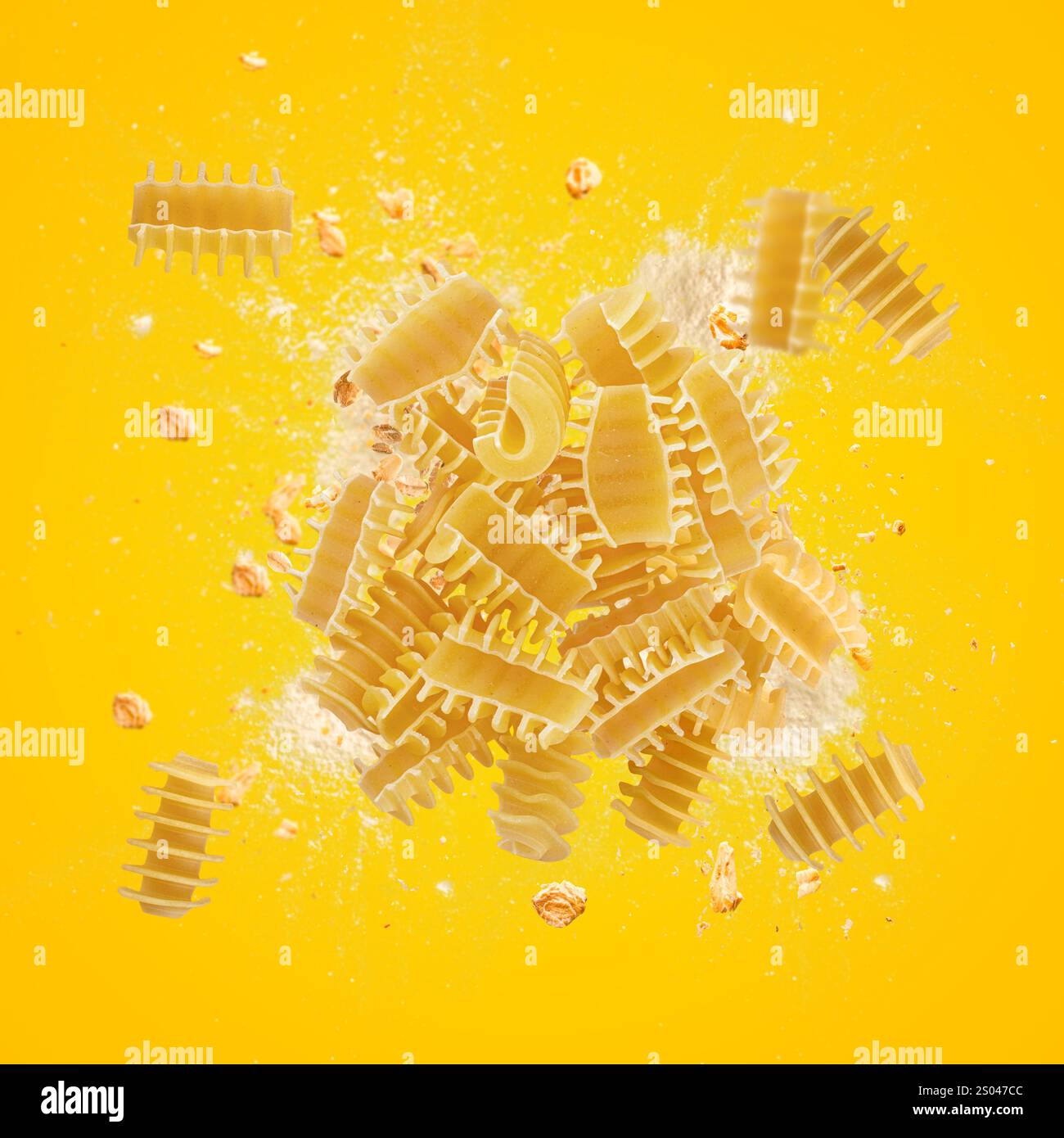 La pasta radiatori esplode con farina e chicchi di grano intero su sfondo giallo Foto Stock