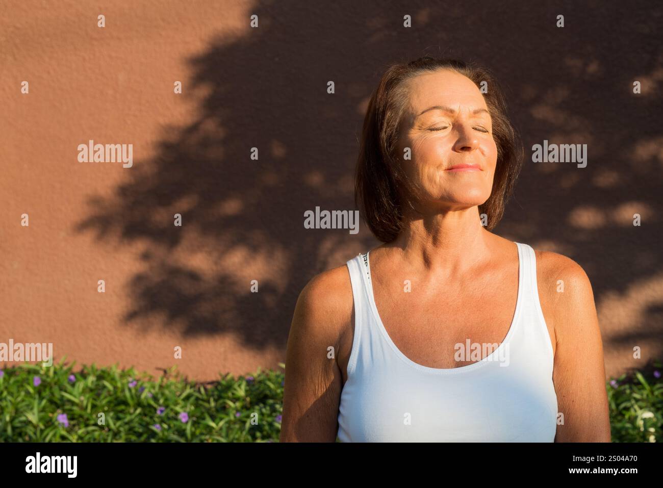 Ritratto di una bella donna matura su sfondo esterno colorato con occhi chiusi Foto Stock