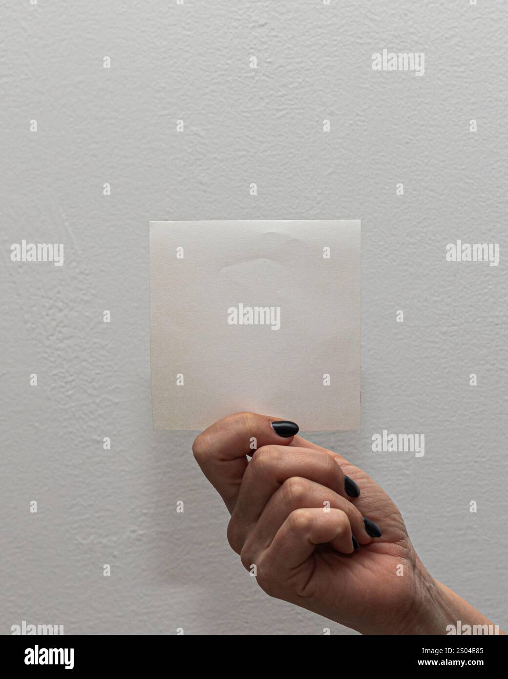 Primo piano di una mano con un foglio bianco vuoto, perfetto per aggiungere testo o grafica, su uno sfondo semplice Foto Stock