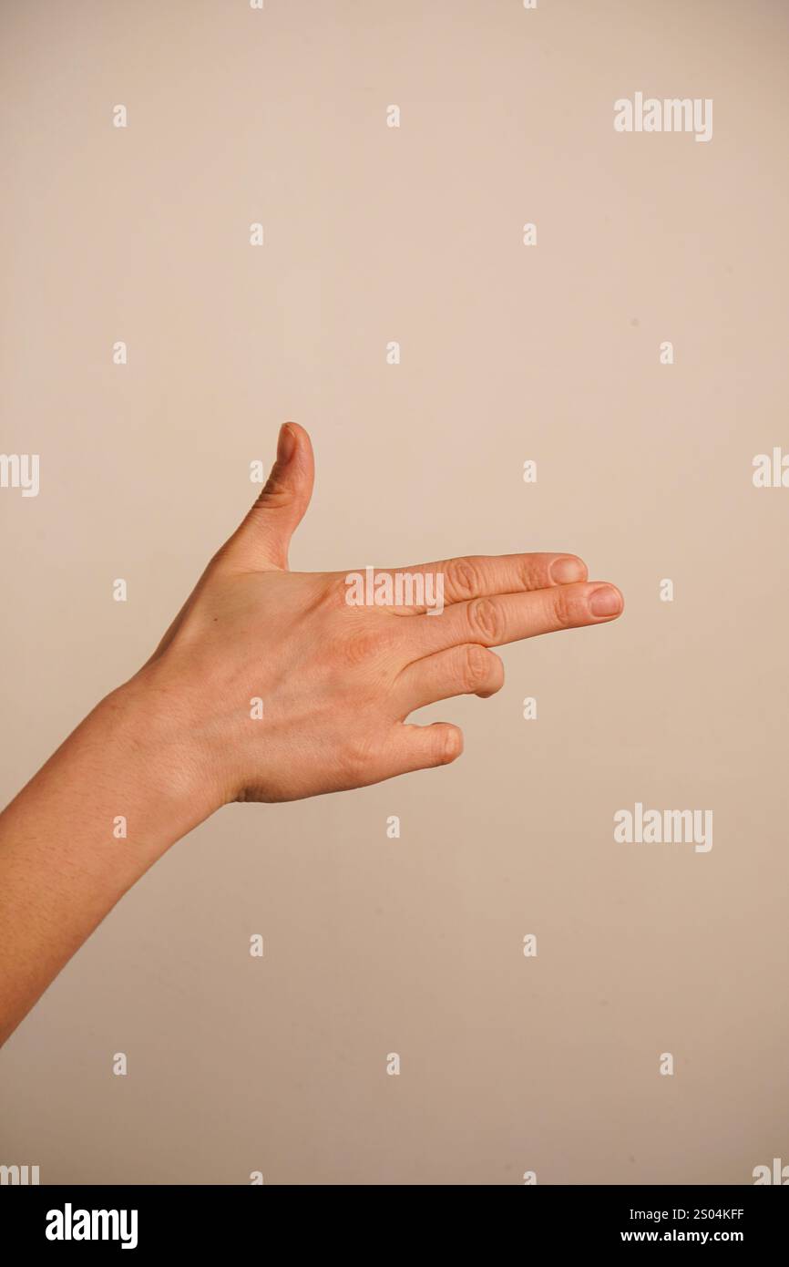 Indicizza e medio dita rivolte verso l'esterno e le due dita inferiori sono piegate nel palmo. Pollice in mano. La mano che punta come una pistola Foto Stock