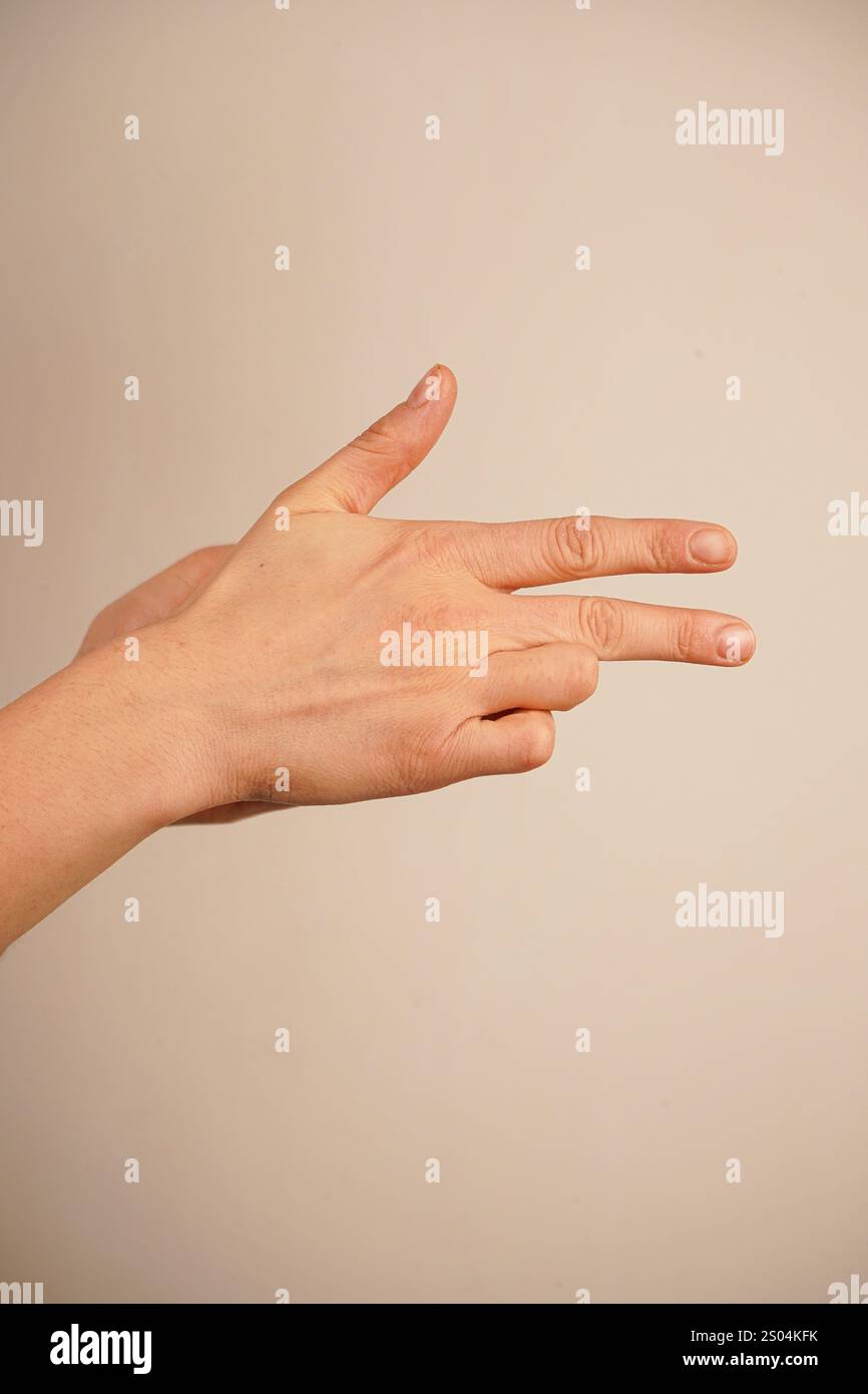 Indicizza e medio dita rivolte verso l'esterno e le due dita inferiori sono piegate nel palmo. Pollice in mano. La mano che punta come una pistola Foto Stock
