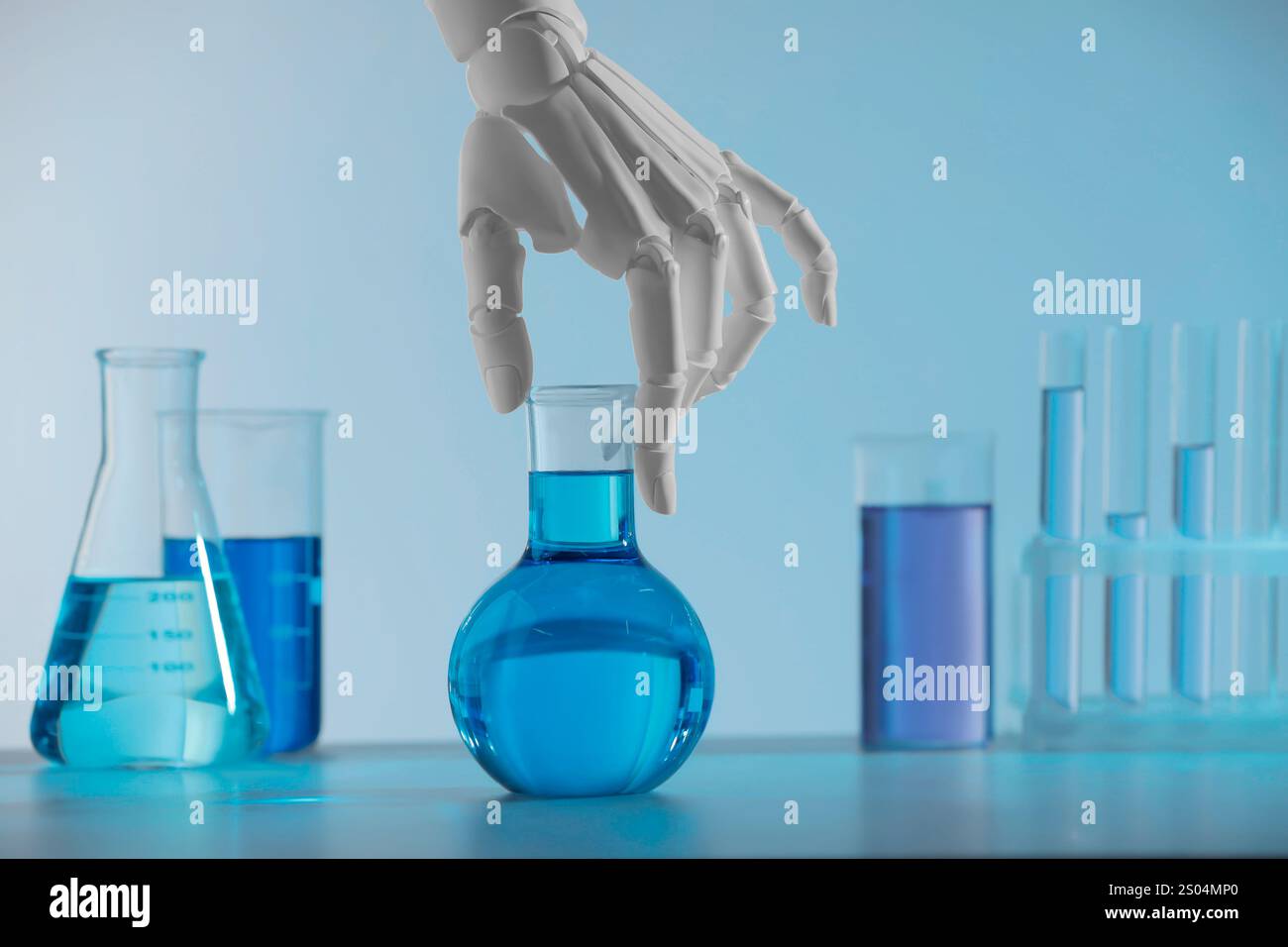 Intelligenza artificiale. Mano robot con matraccio e altra vetreria da laboratorio con liquidi sul tavolo su sfondo azzurro Foto Stock