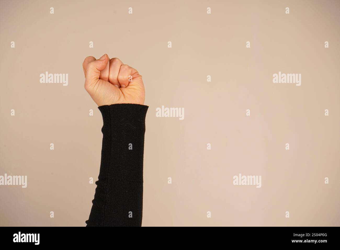 La mano forma un pugno forte, simboleggiando forza e protesta. Questo gesto iconico parla di spirito combattivo. Lo sfondo semplice migliora il powe Foto Stock