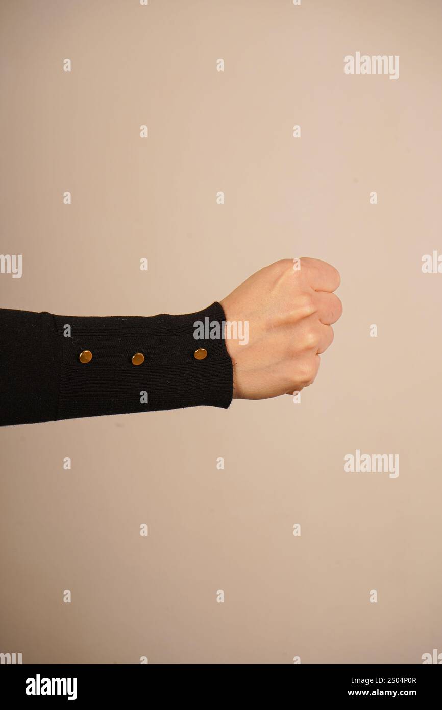La mano forma un pugno forte, simboleggiando forza e protesta. Questo gesto iconico parla di spirito combattivo. Lo sfondo semplice migliora il powe Foto Stock