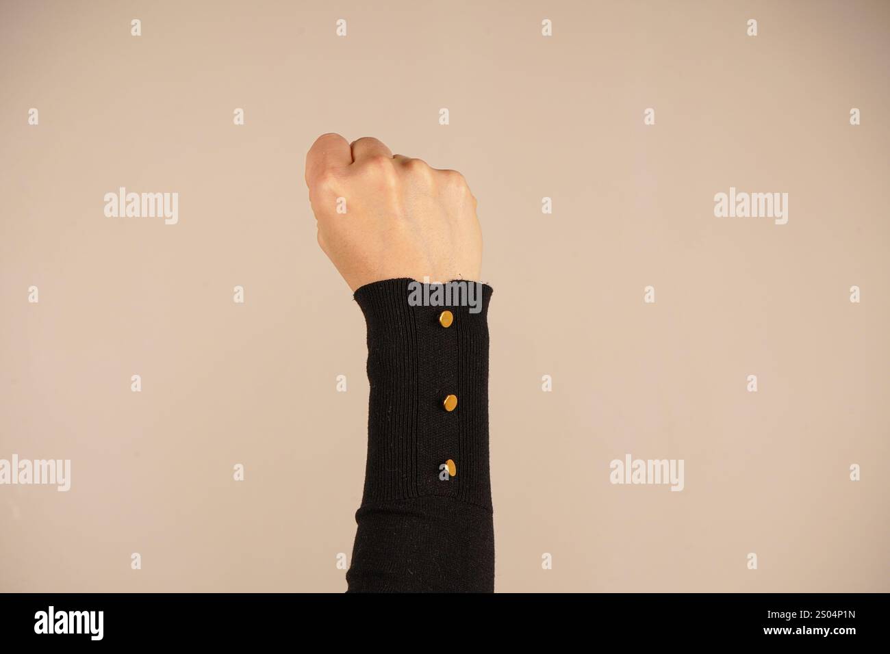 La mano forma un pugno forte, simboleggiando forza e protesta. Questo gesto iconico parla di spirito combattivo. Lo sfondo semplice migliora il powe Foto Stock