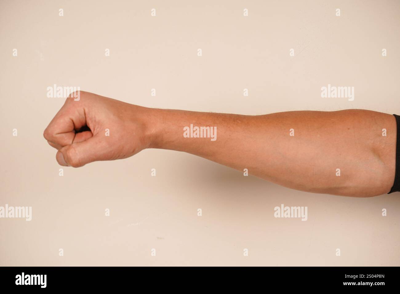 La mano forma un pugno forte, simboleggiando forza e protesta. Questo gesto iconico parla di spirito combattivo. Lo sfondo semplice migliora il powe Foto Stock