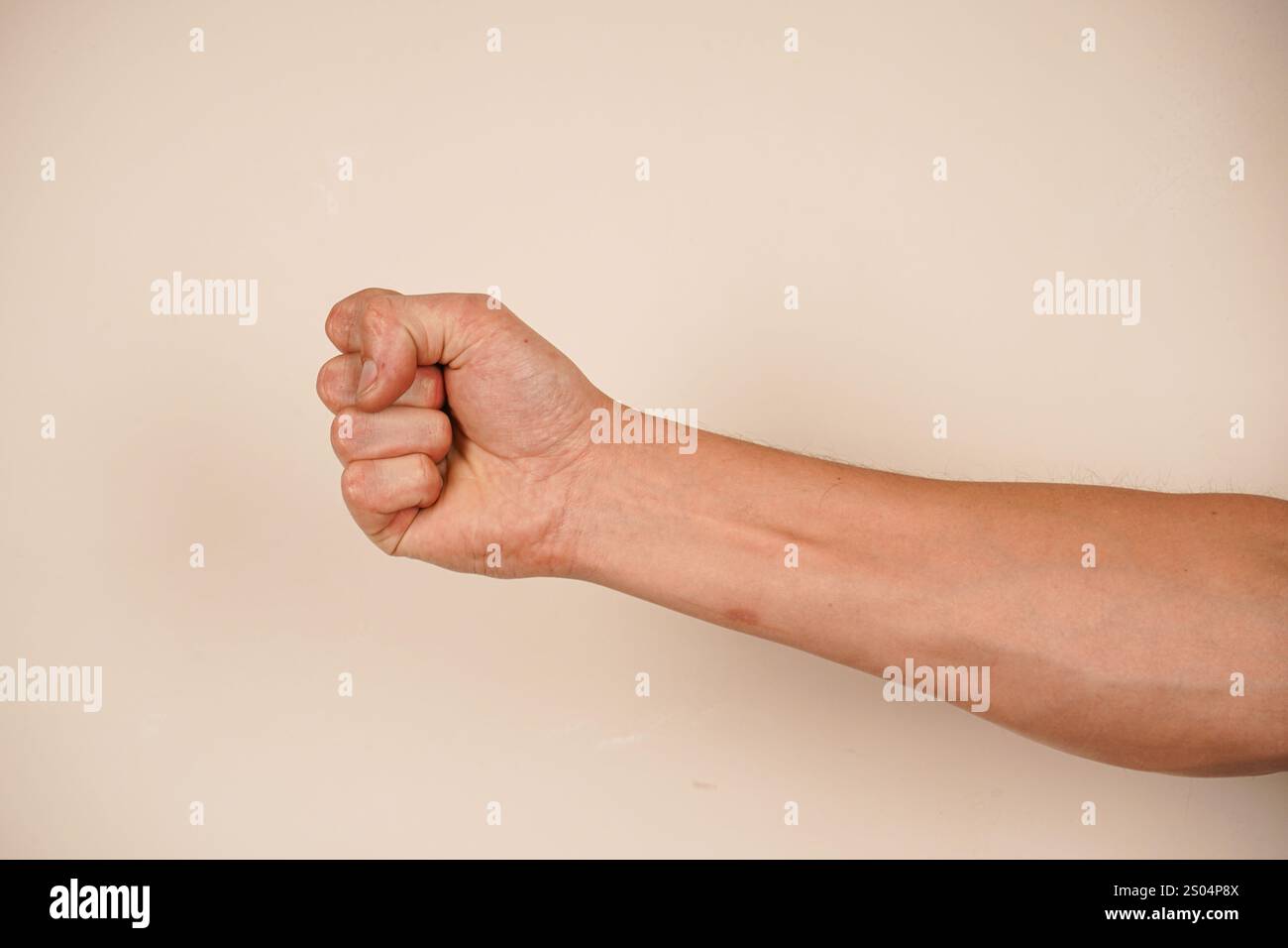 La mano forma un pugno forte, simboleggiando forza e protesta. Questo gesto iconico parla di spirito combattivo. Lo sfondo semplice migliora il powe Foto Stock