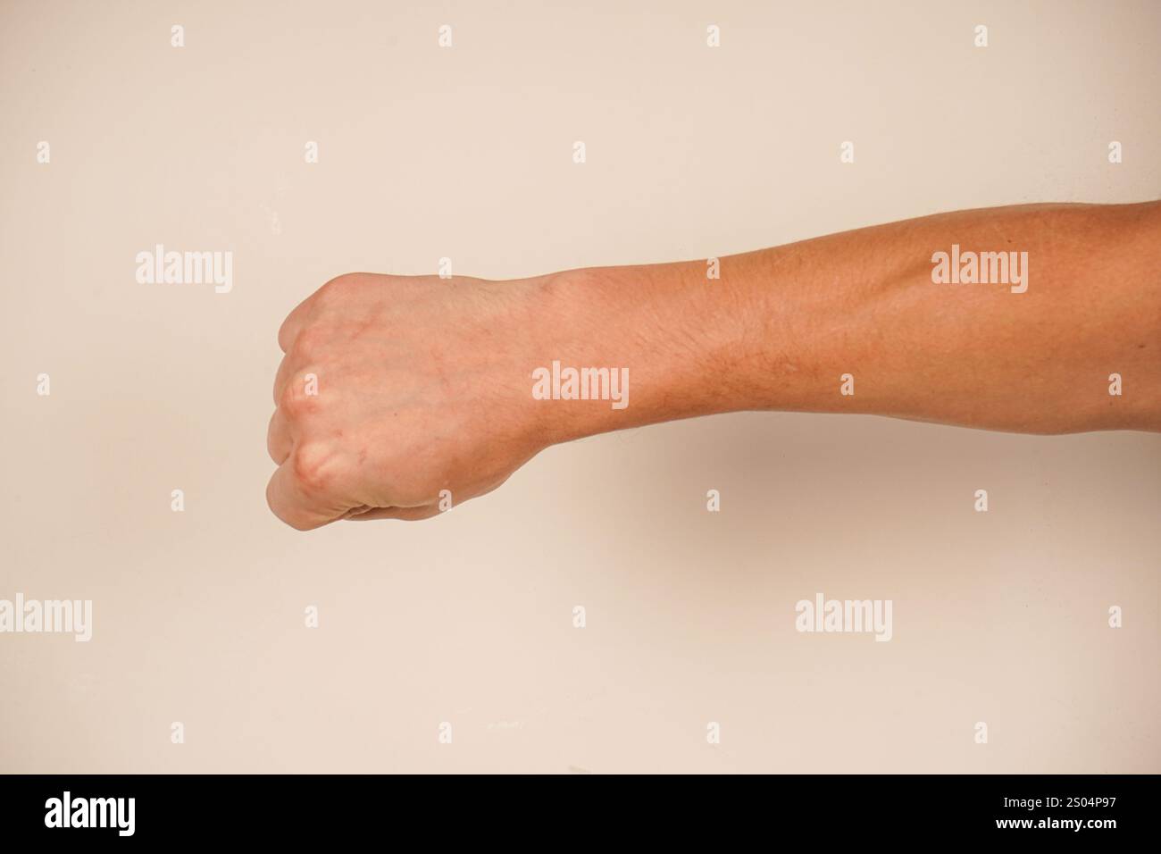 La mano forma un pugno forte, simboleggiando forza e protesta. Questo gesto iconico parla di spirito combattivo. Lo sfondo semplice migliora il powe Foto Stock