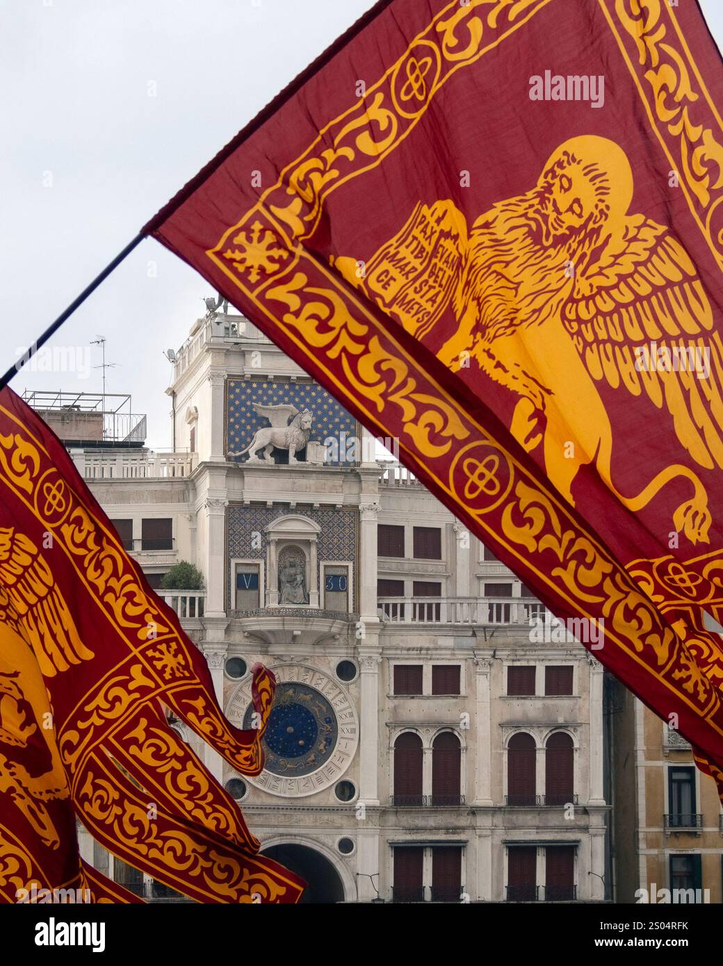 VENEZIA, ITALIA - 5 MAGGIO 2015: La Torre dell'Orologio in Piazza San Marco vista attraverso le bandiere del Leone alato Foto Stock