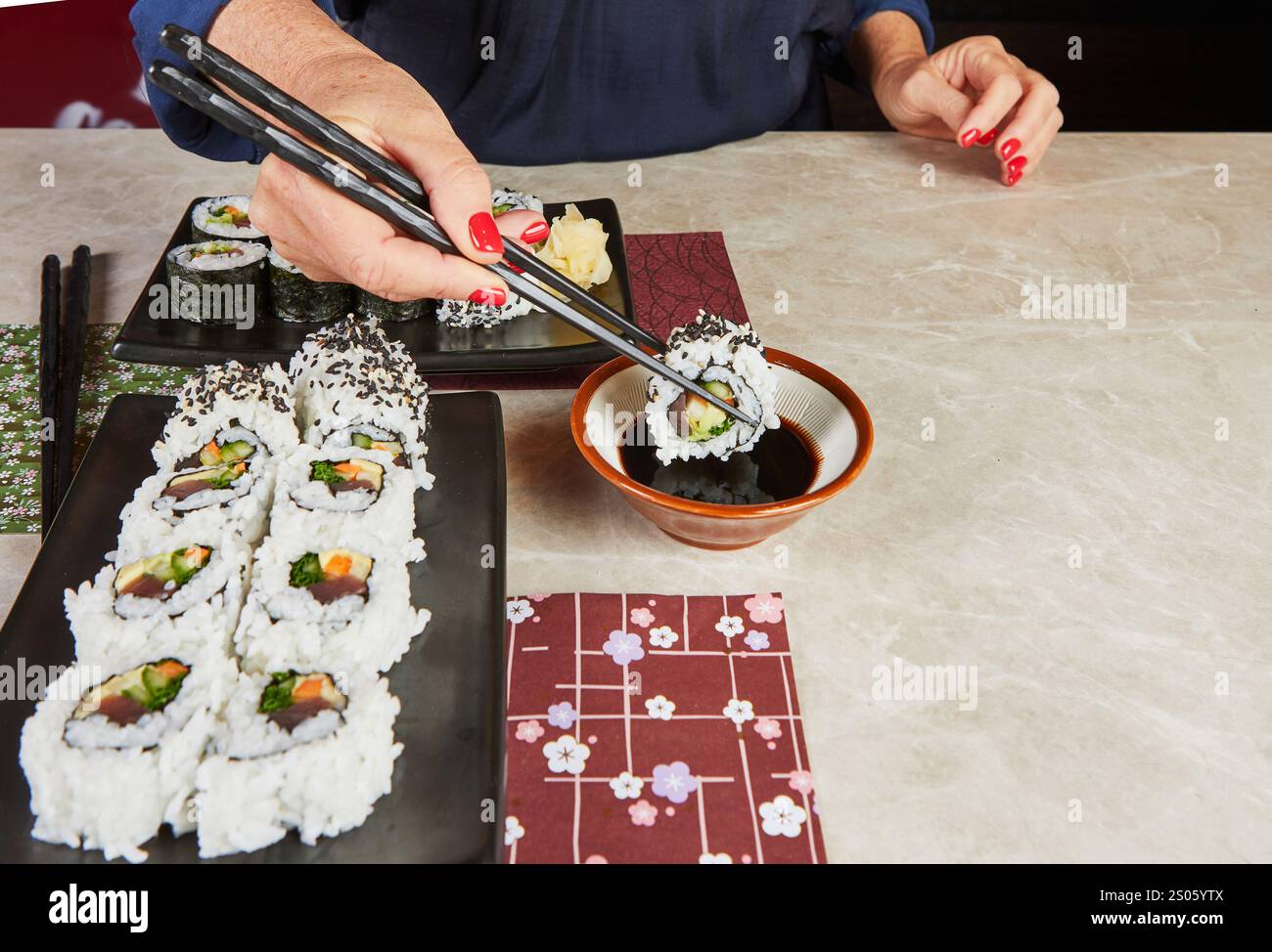Un elegante piatto di sushi servito con contorni tradizionali giapponesi, che includono salsa di soia e zenzero sottaceto, per un'esperienza culinaria completa. Foto Stock