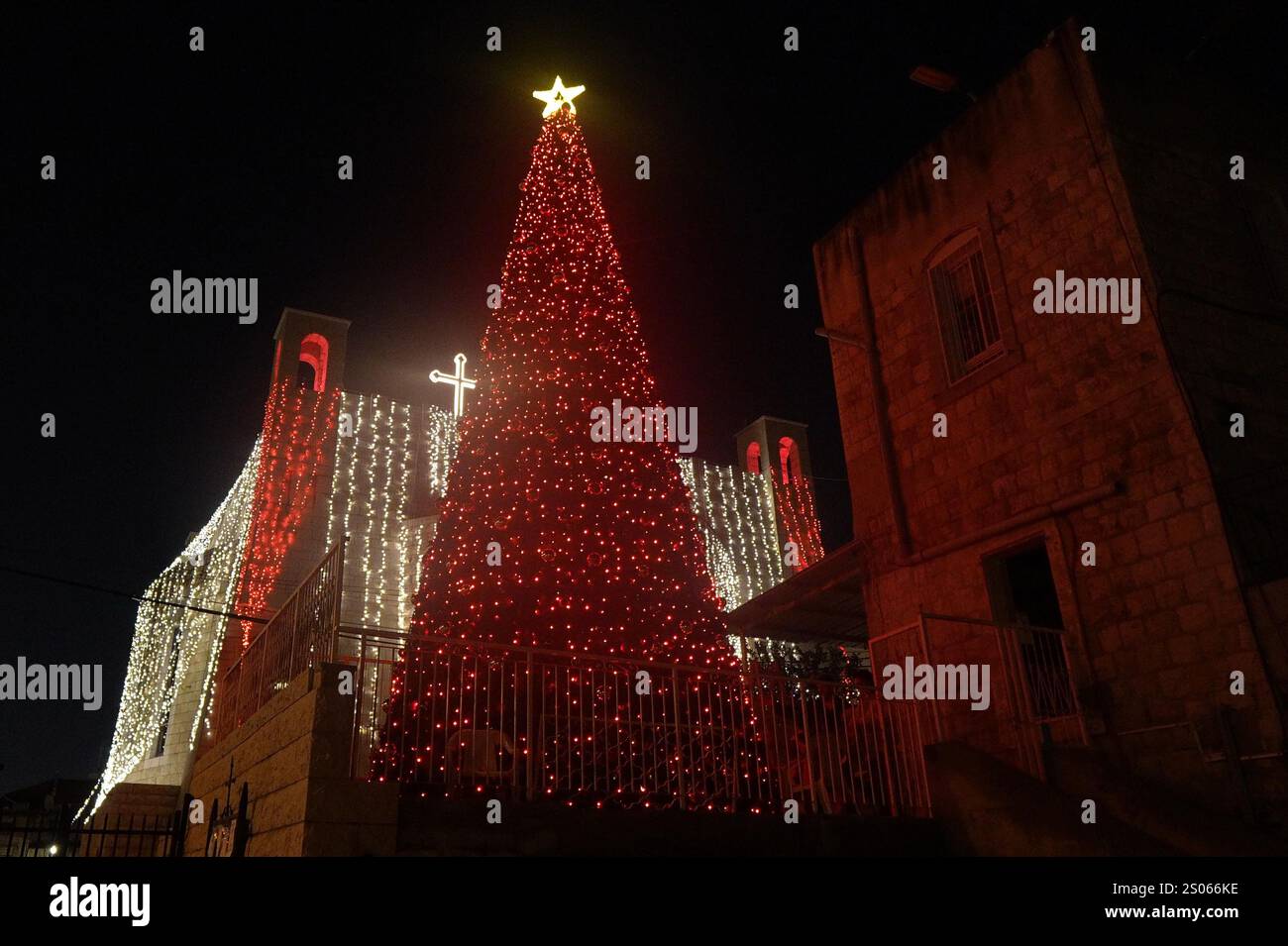 Un albero di Natale decorato esposto all'esterno della chiesa greco-ortodossa "Giovanni Battista", situata nella Colonia tedesca il 24 dicembre 2024 ad Haifa, Israele. Foto Stock