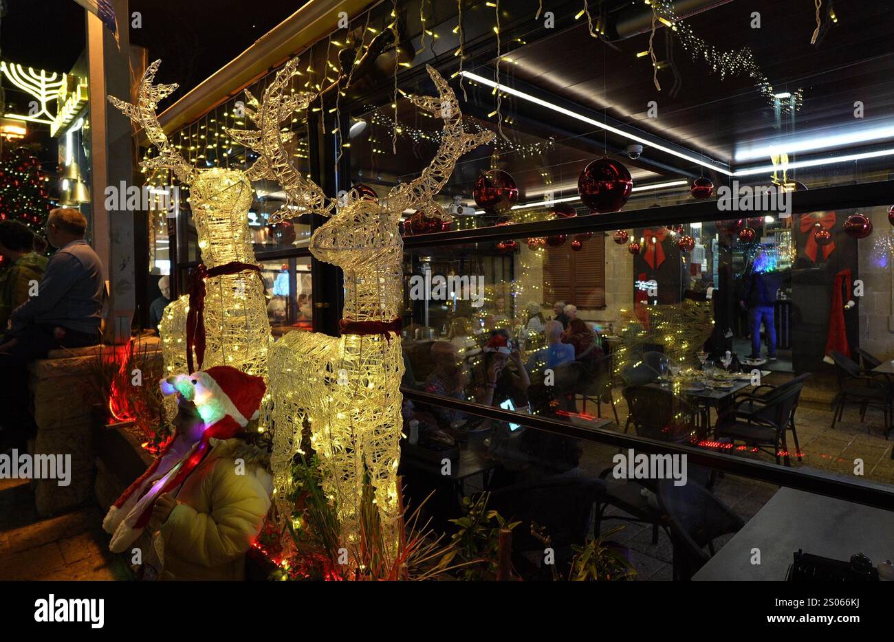 Le renne illuminate si trovano fuori da un ristorante nel quartiere delle colonie tedesche, mentre la città si prepara per Natale il 24 dicembre 2024 ad Haifa, Israele. Foto Stock