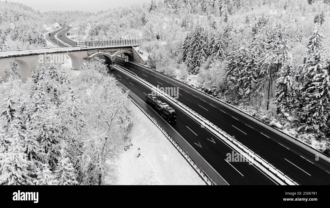 Autostrada coperta di neve e ponte nella foresta invernale Foto Stock